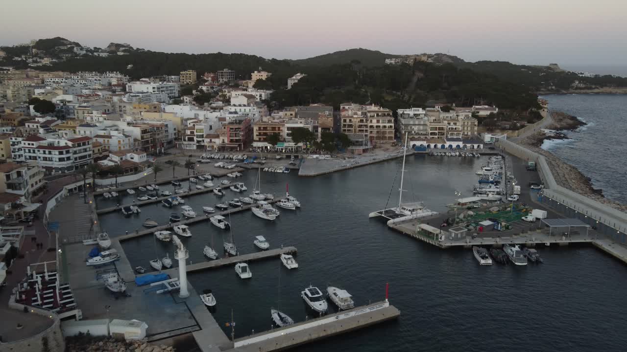 Avvicinamento aereo al porto turistico di Cala Rajada al tramonto, Maiorca, Spagna.