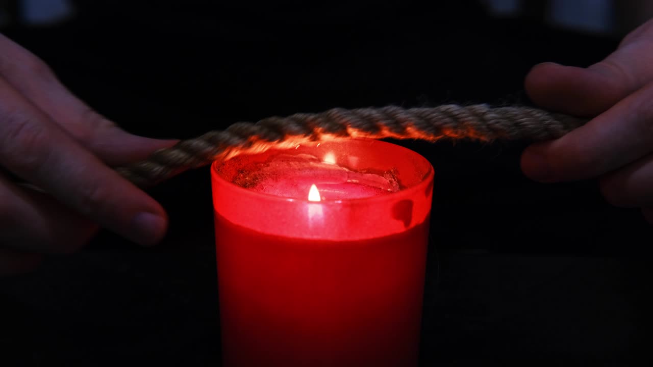quemando una cuerda de yute en el fuego de una vela para el ritual shibari