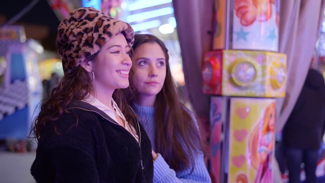 Two young women enjoying an amusement park at night