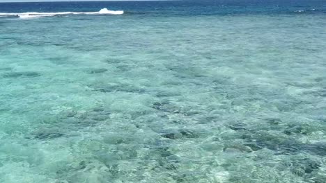 Flying-low-over-people-swimming-in-clear-ocean-water