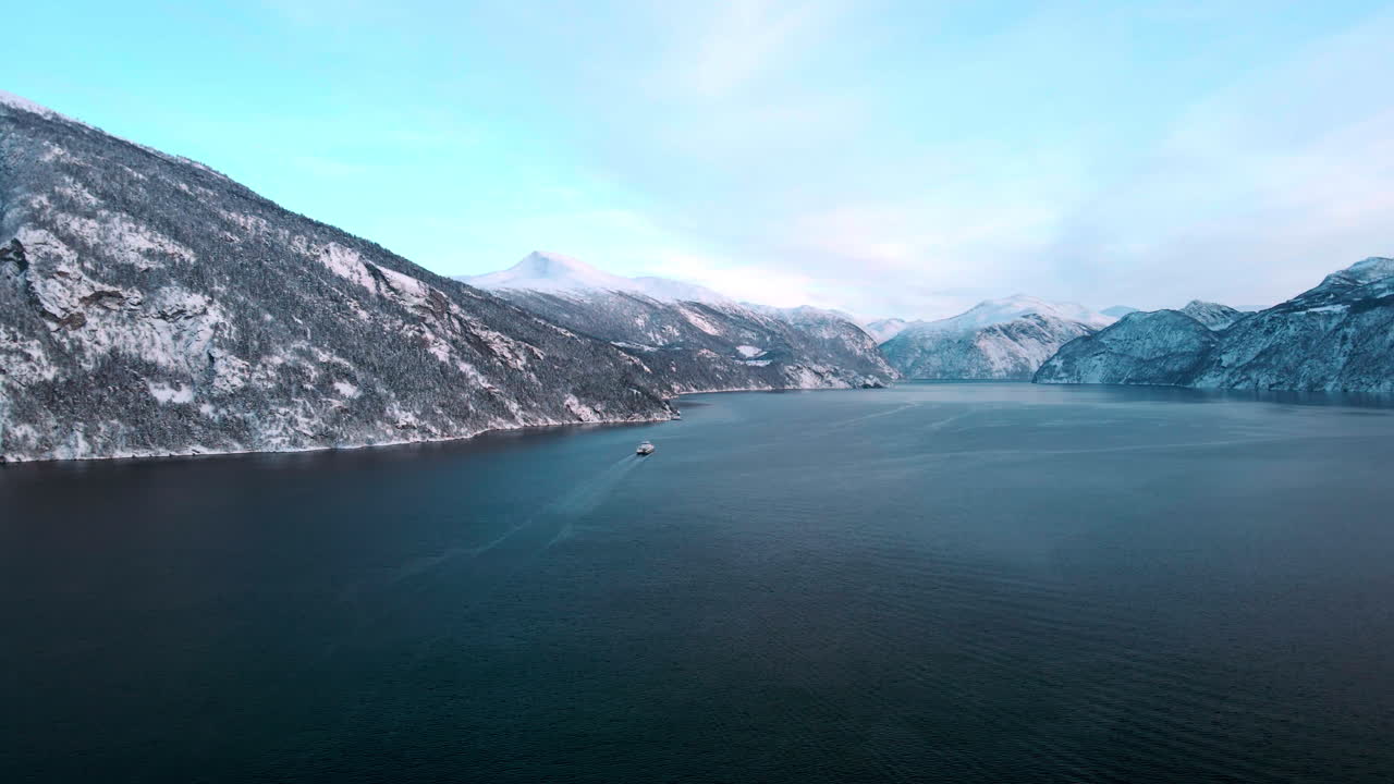 Drone over norwegian fjord with a ferry in it on a sunny winter day