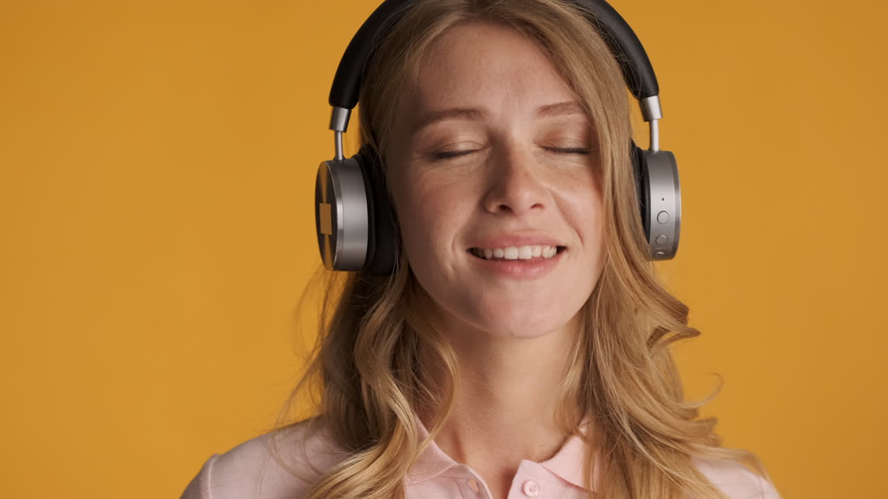 una mujer caucásica con auriculares escuchando música.