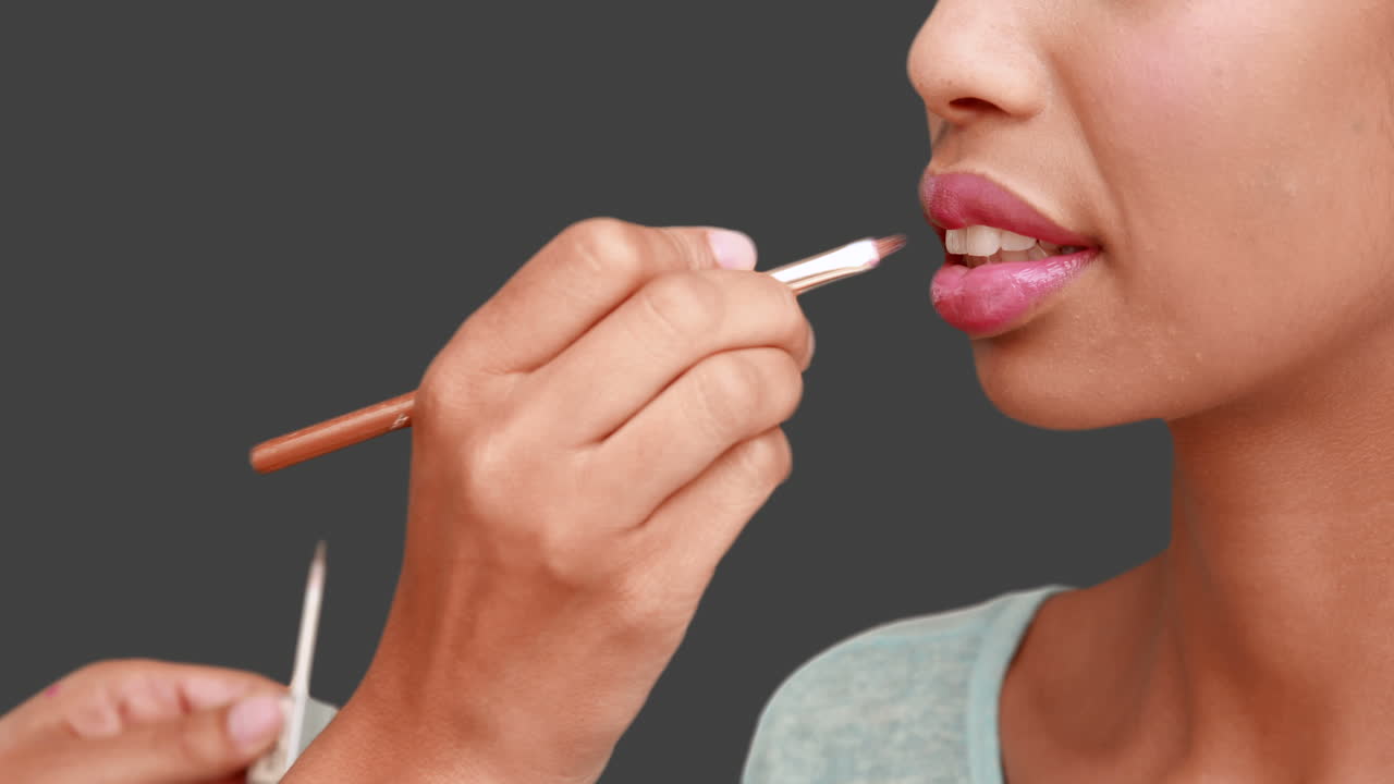 artista de maquillaje poniendo brillo para los labios en la cara de las modelos