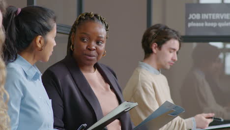 multiethnic women having talk in line before job interview