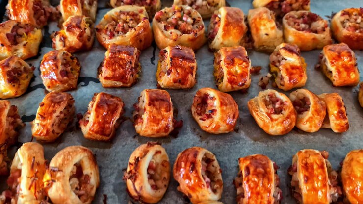Featuring of numerous golden colored pastries garnished with nuts and savory fillings on baking sheet