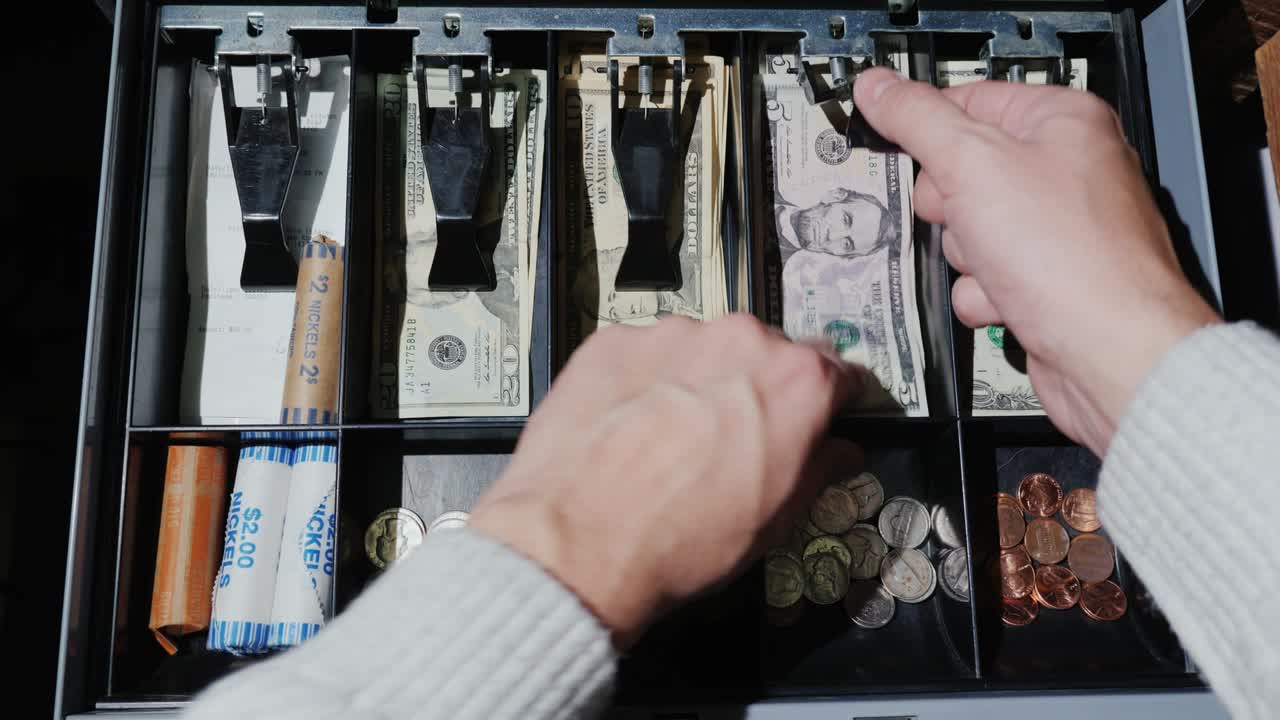 el cajero pone el dinero en la caja registradora y toma el cambio.