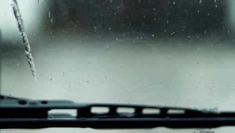 a close up view of a windshield wiper wiping as rain keeps falling