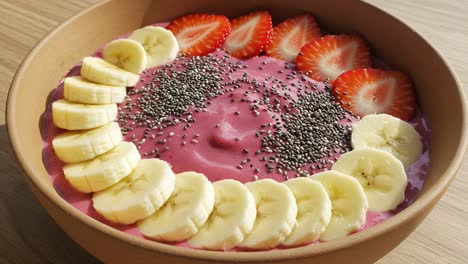 delicious and colorful smoothie bowl with fresh strawberries, bananas, and chia seeds served in a wooden bowl