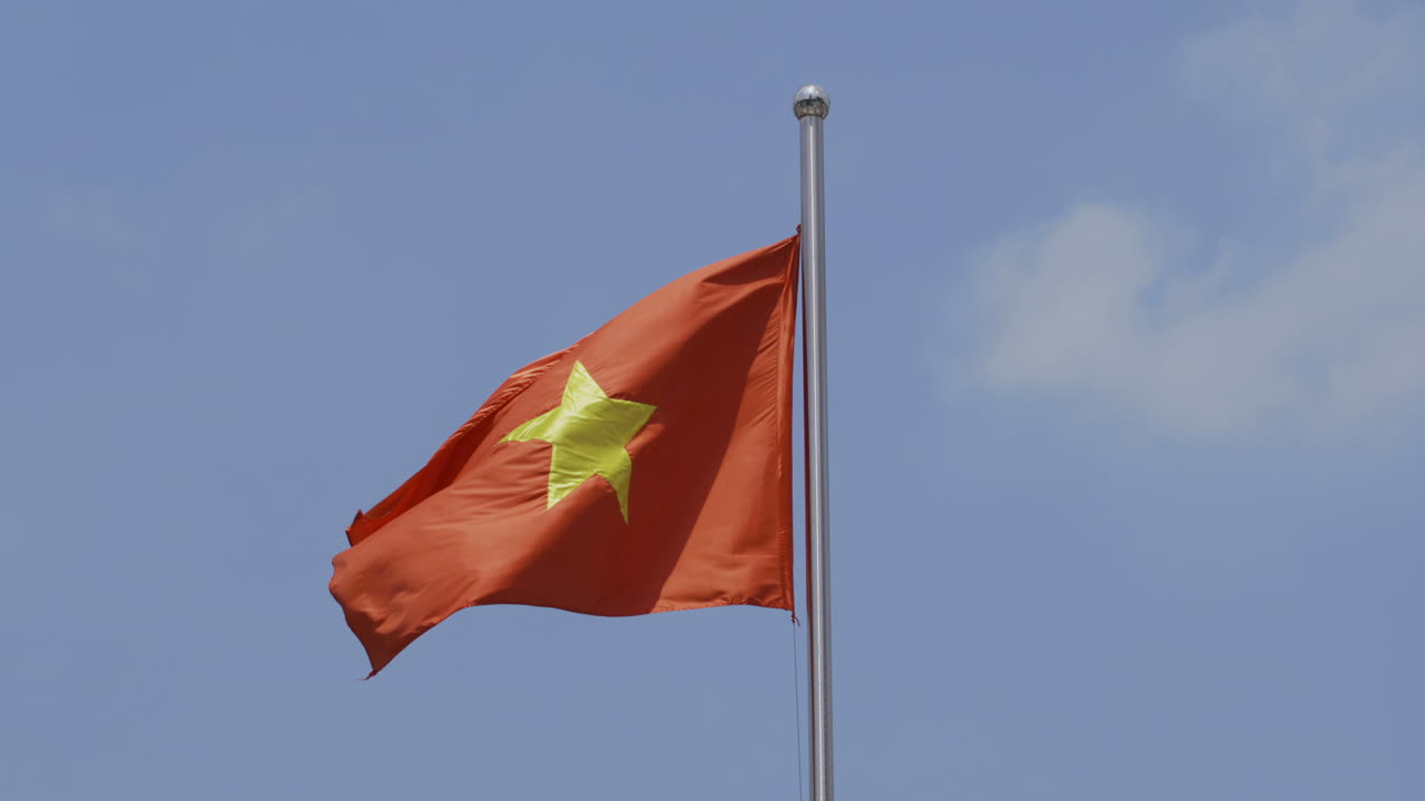 푸른 하늘과 구름 배경으로 밝은 태양 아래 베트남 국기의 4k 비디오