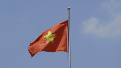 video 4k de la bandera nacional de vietnam bajo un sol brillante con cielo azul y fondo de nubes