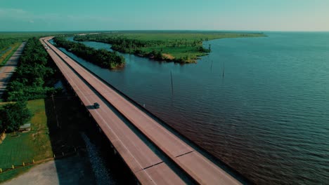 drone captures a static aerial view of a bridge over lake maurepas with wetlands, traffic, and serene southern scenery.