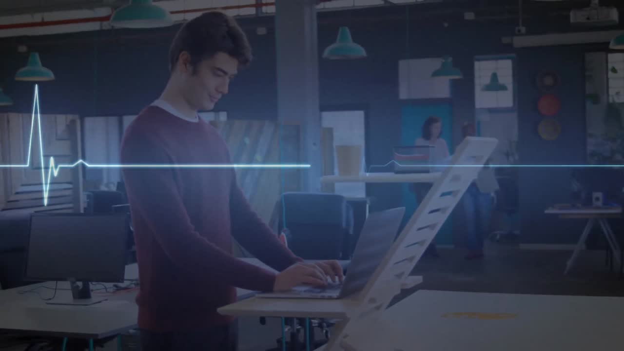 animación de un monitor de frecuencia cardíaca azul brillante, sobre un hombre que usa una computadora portátil en un escritorio de pie en la oficina