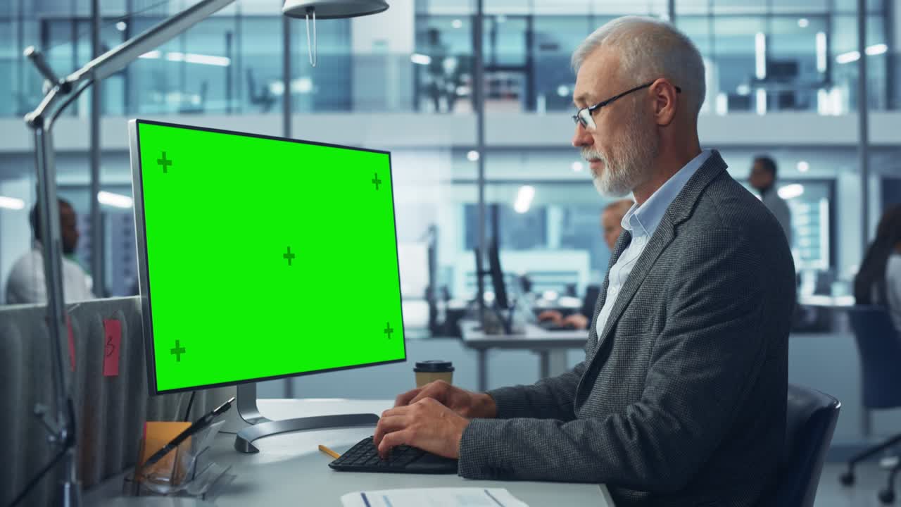 ufficio moderno diversificato: tecnico informatico caucasico senior che utilizza un computer desktop con schermo chiave chroma verde. ingegnere amministratore lavoro sullo sviluppo di e-commerce, marketing di progetti, analisi di big data