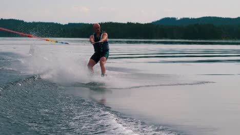 Primer-Plano-En-Cámara-Lenta-De-Un-Joven-Montando-Un-Wakeboard-Después-De-Un-Barco-Deportivo-En-El-Archipiélago-Sueco-En-El-Verano