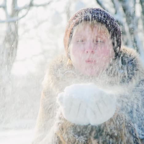 a woman blows snow out of her hands