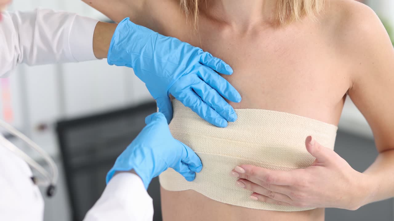 Medical professional examining patient's bandaged chest