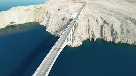flying drone backwards the view over pag bridge and white stoney island on summer morning in croatia with blue adriatic sea
