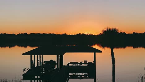 sunrise over lake with dock and boat