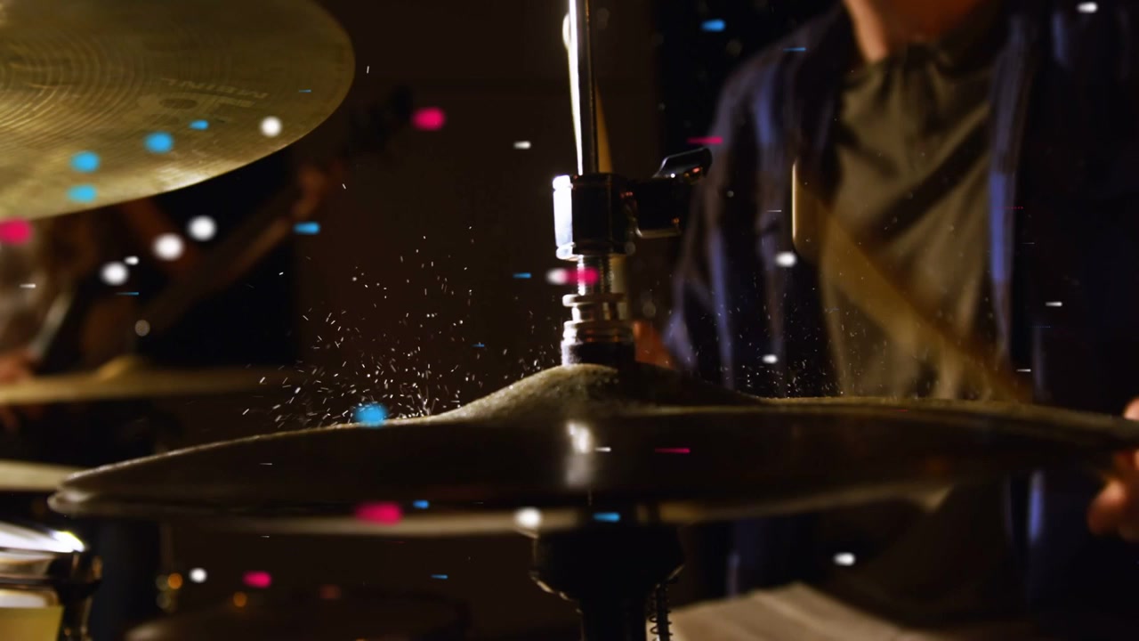 Vídeo vertical: Baterista levantando baqueta e batendo no prato, espalhando luz, enquanto a guitarra toca mantendo o ritmo.
