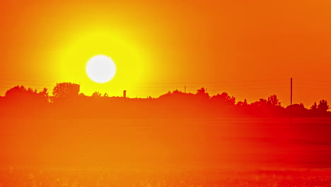 vurige, gouden, gloeiende zonsondergang op een wazige avond op het platteland - time-lapse