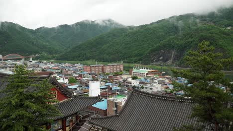 panorámica sobre el punto alto del baile panorámico de la ciudad de danyang, edificio del templo tradicional coreano en primer plano contra las montañas en una neblina después de la lluvia
