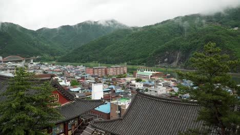 panning on danyang city panorama prom high point, korean traditional temple building in foreground against mountains in a haze after rain