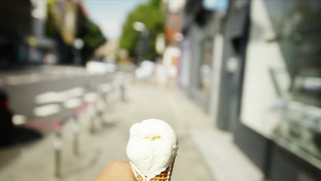 man holding ice-cream point of view walking through city