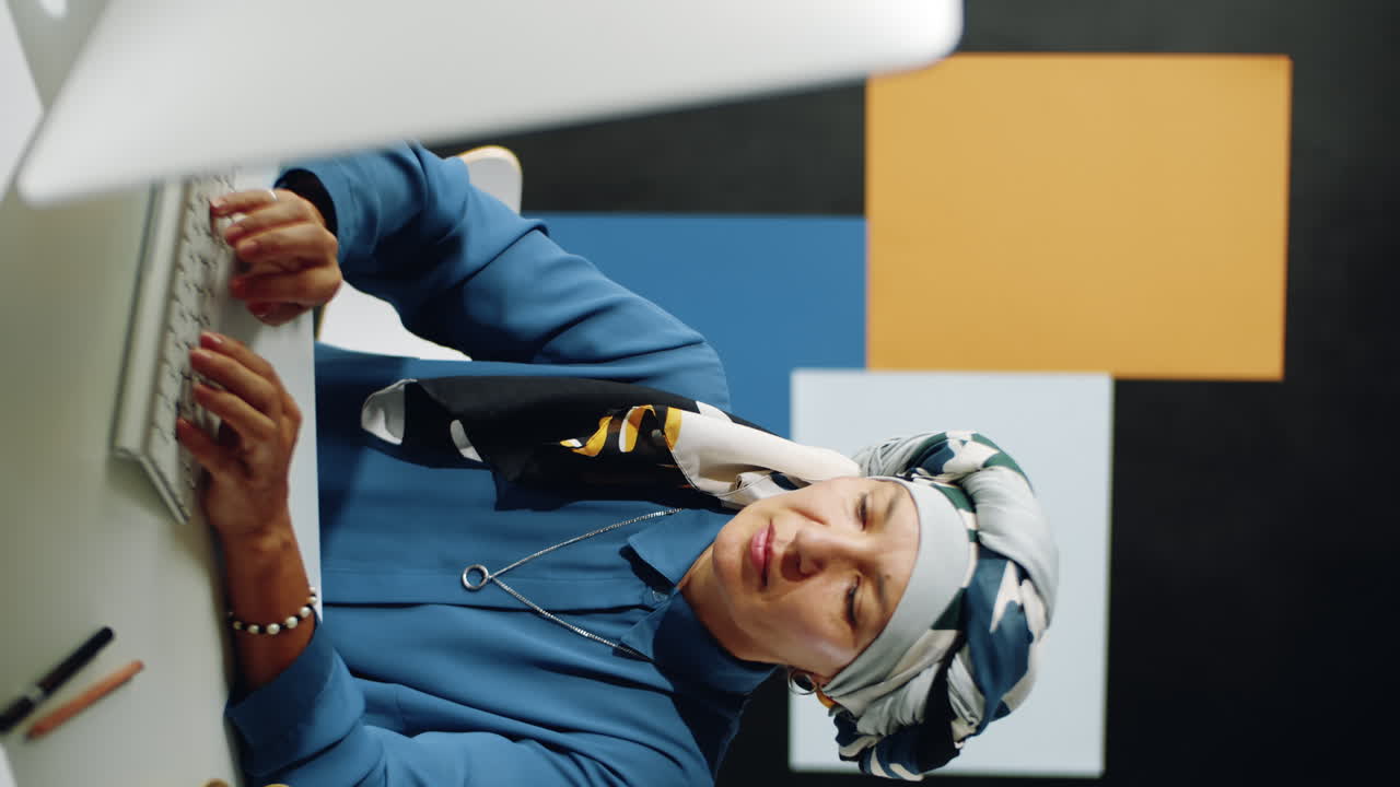 mujer musulmana madura usando la computadora vertical