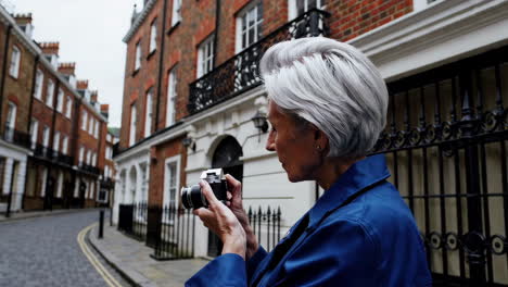 elderly woman taking pictures with a vintage camera on a city street