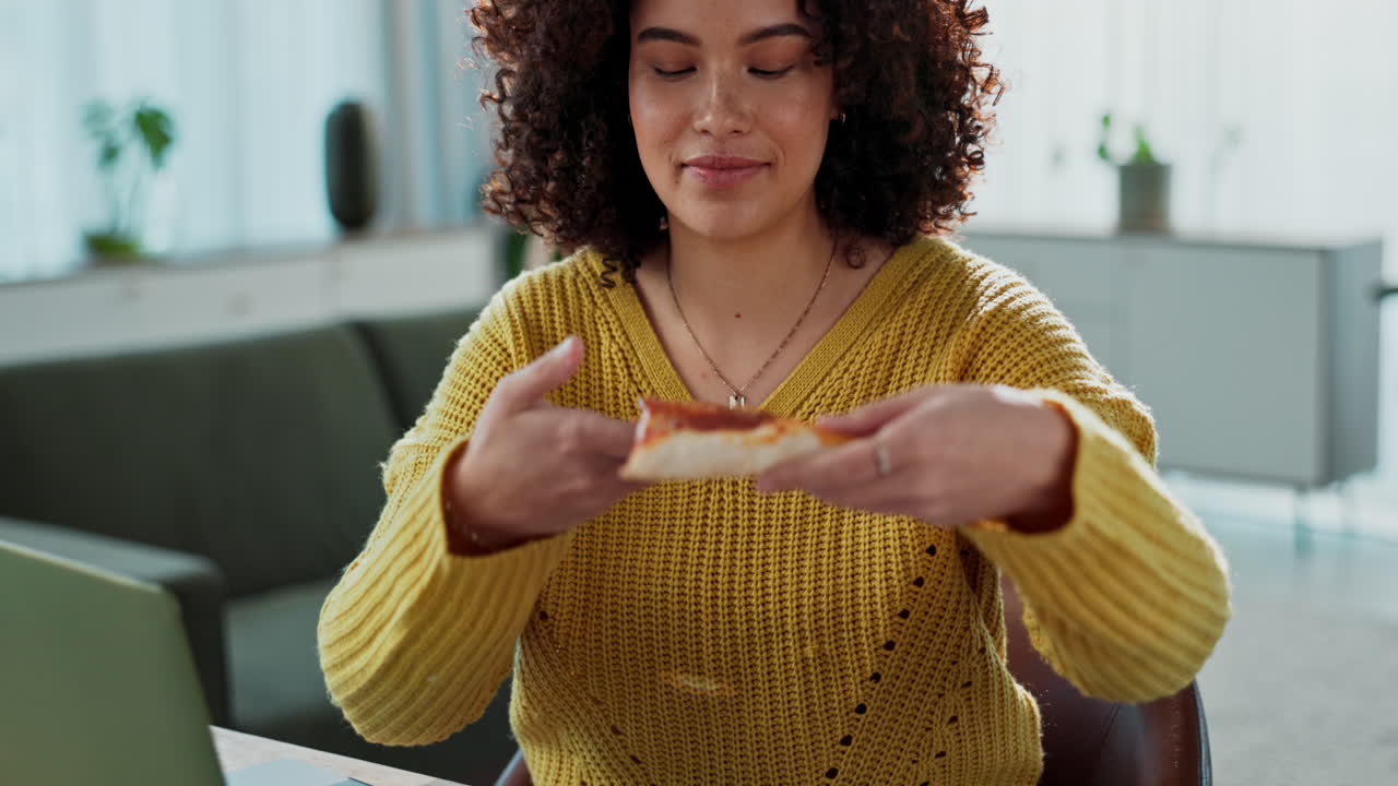 Woman eating pizza while working on laptop