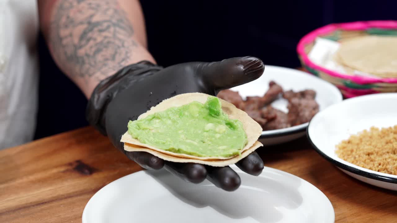 Serving sauce on top of a tortilla with avocado guacamole Mexican chef