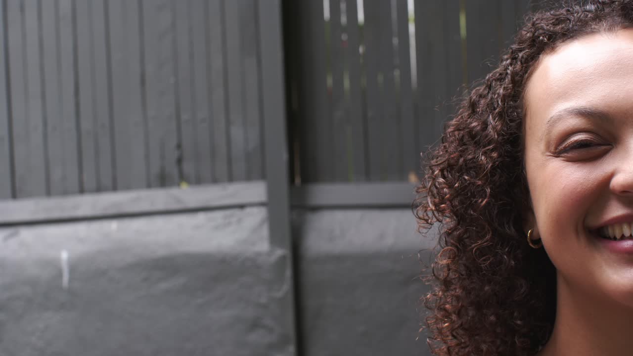 Afro-Amerikaanse vrouw poseert voor de camera, komt in beeld en lacht bij een donker hek, kopieerruimte