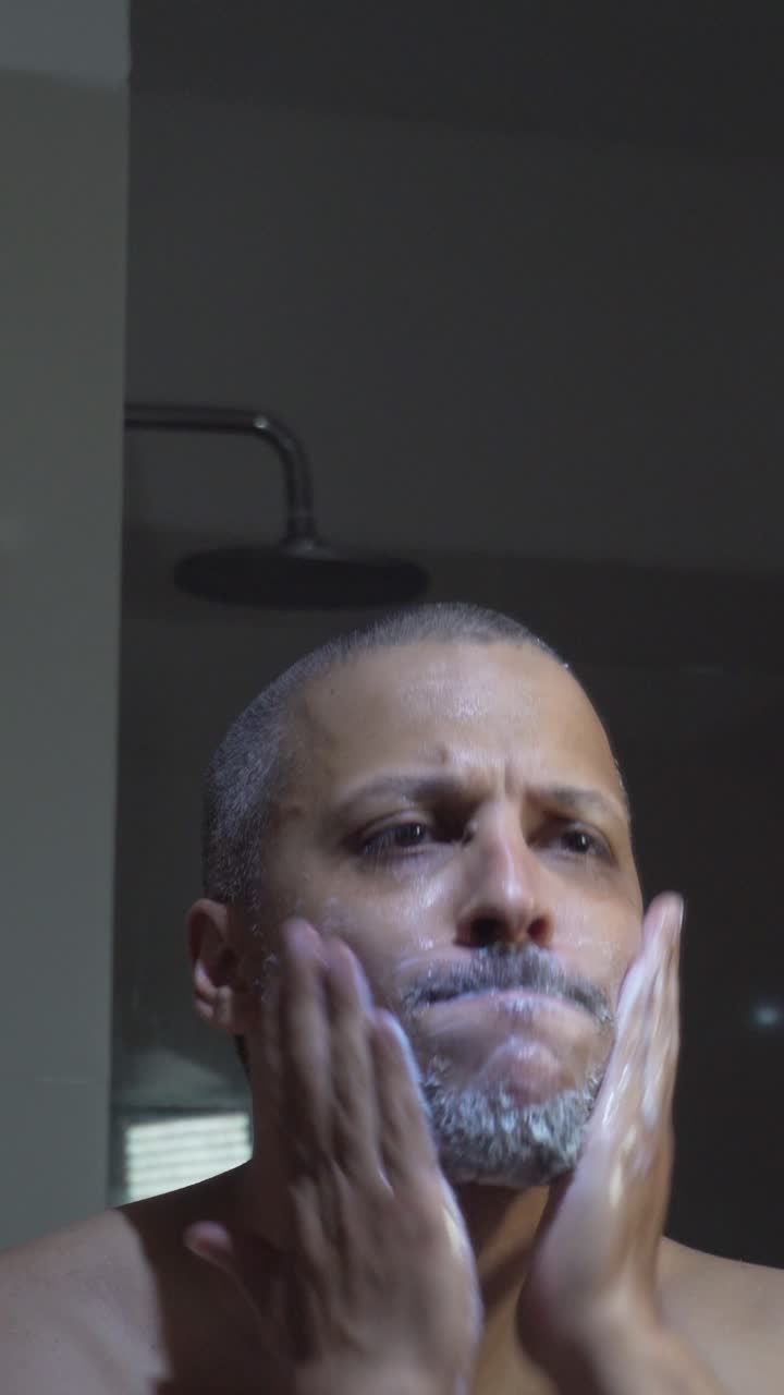 Uomo che applica la crema da barba sul viso in bagno