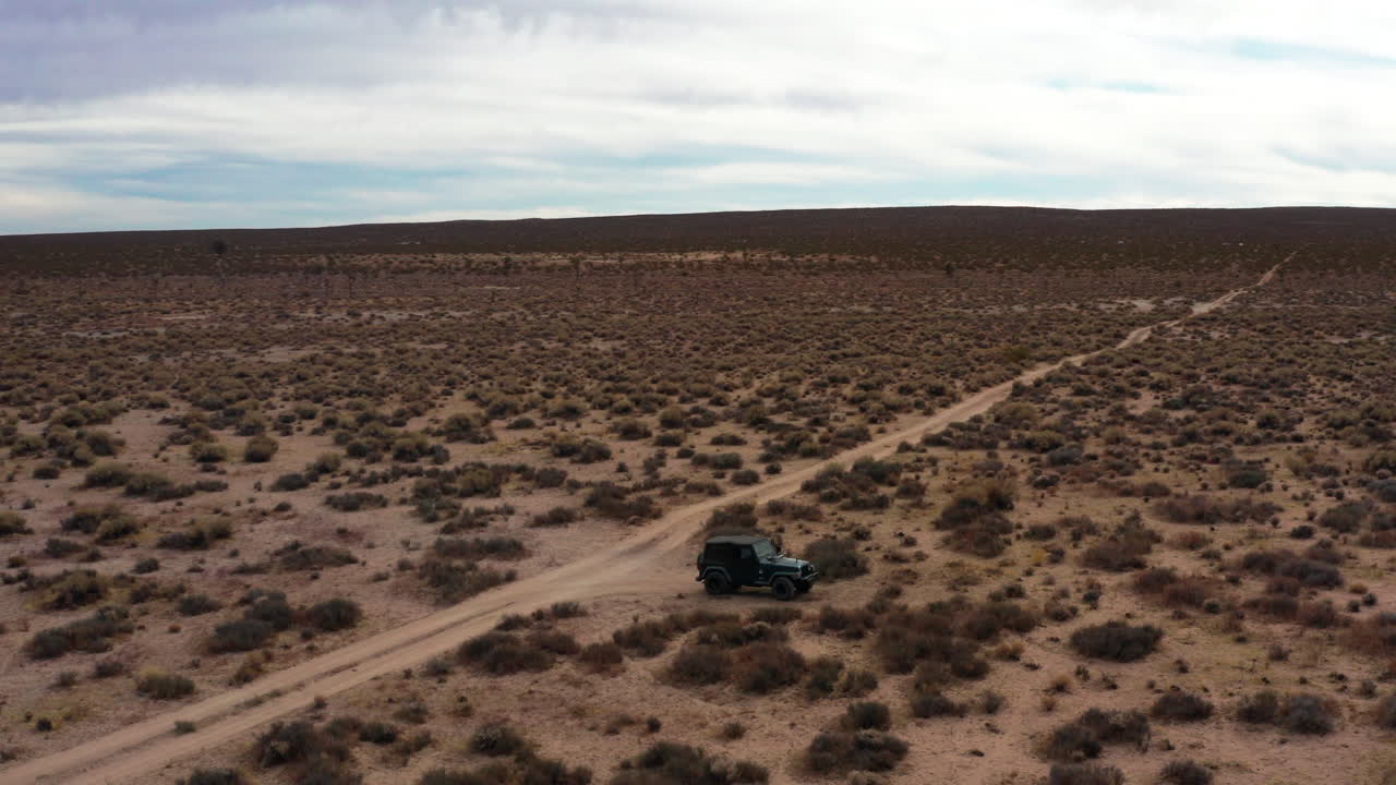 vista aérea en órbita de un jeep estacionado en medio del desierto de mojave - el hombre camina hacia el terreno accidentado