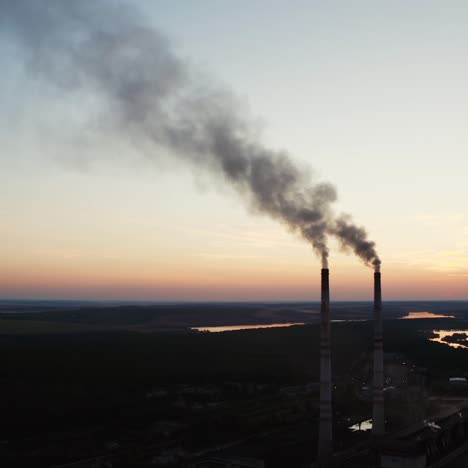 ecological disaster. dirty emissions from industrial pipes on the natural environment in the evening. factory near the river at sunset.