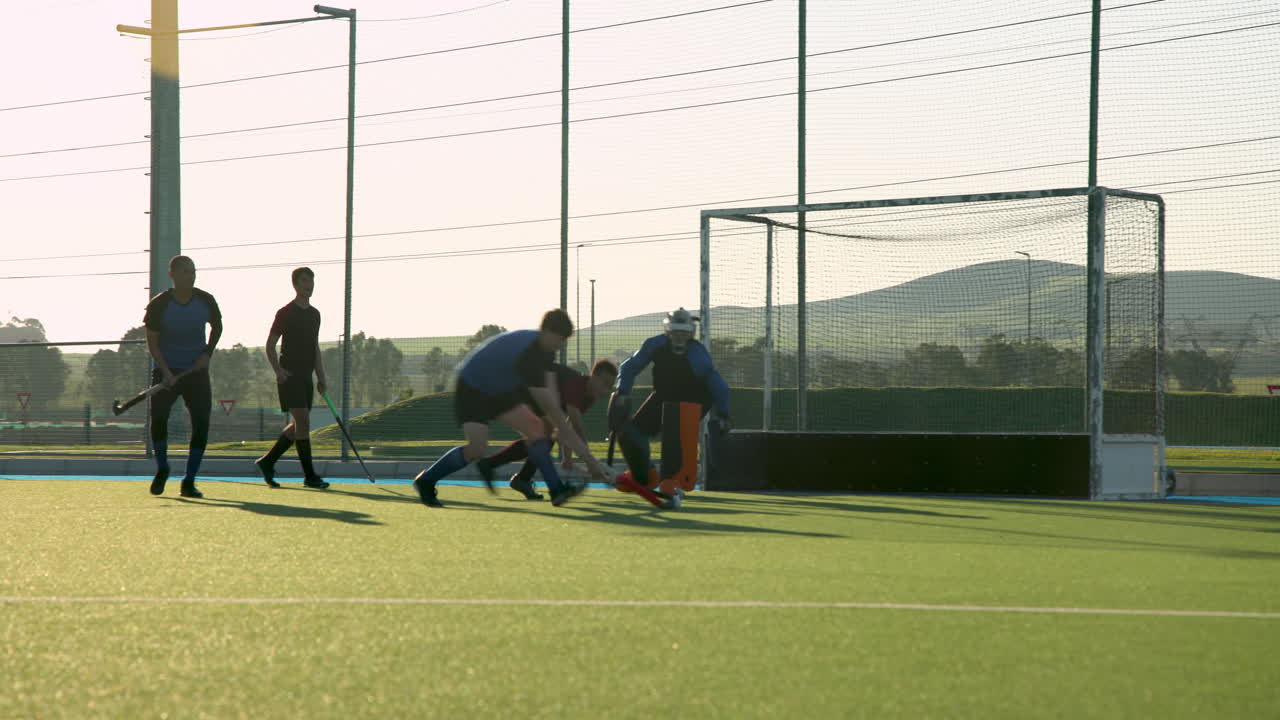 Playing field hockey, male players competing near goalpost during match