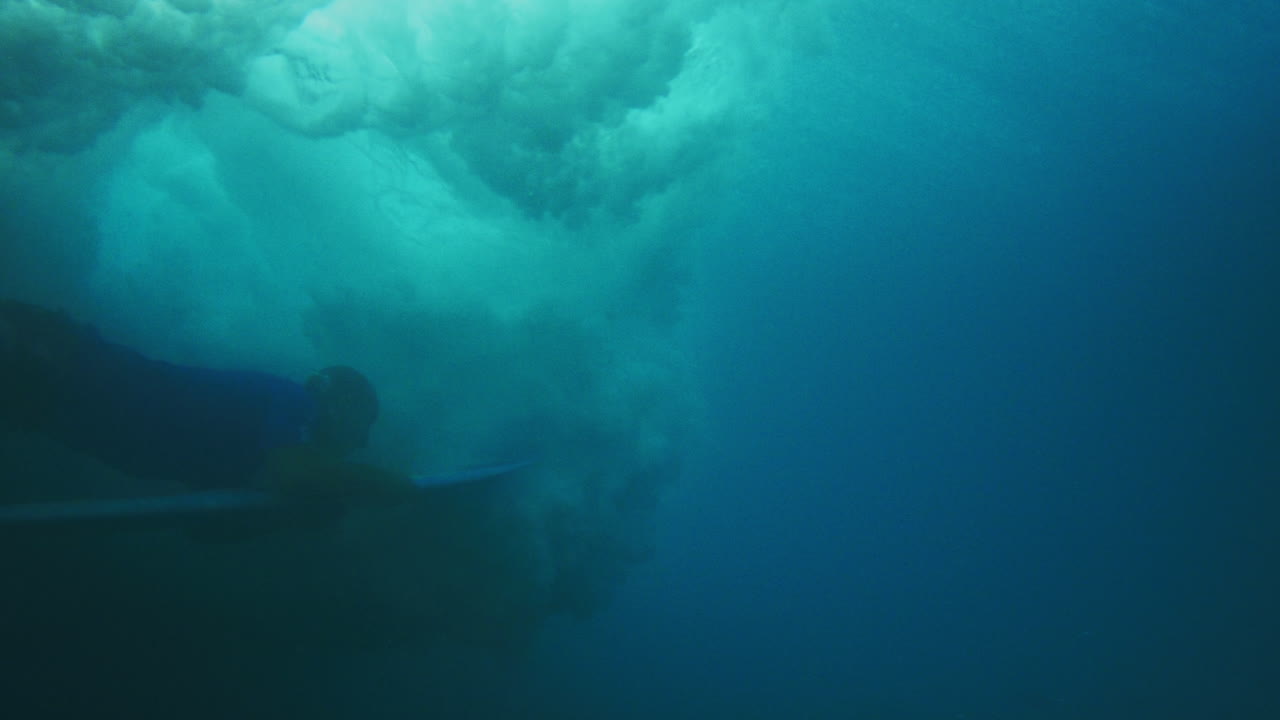 el surfista empuja la tabla por debajo para bucear bajo una fuerte onda de choque