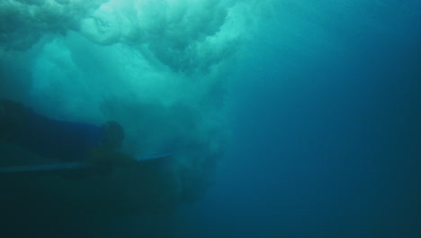 el surfista empuja la tabla por debajo para bucear bajo una fuerte onda de choque