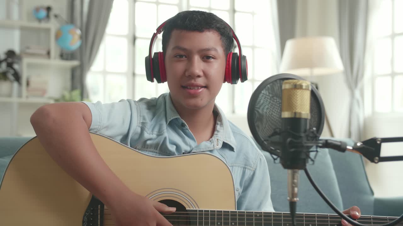Teenage Boy Playing Acoustic Guitar and Singing into Microphone at Home