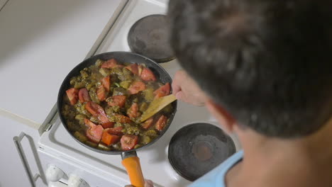 man stewing tomatoes mushrooms and potatoes in pan