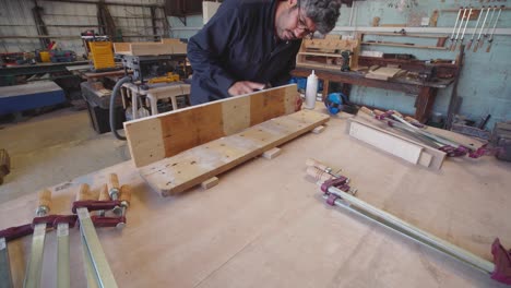 Carpenter-using-clamps-and-glue-to-put-together-recycled-pallet