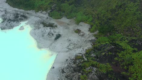 árboles marchitos en una playa rodeada por un lago de azufre azul en kawah putih en bandung indonesia, aéreo