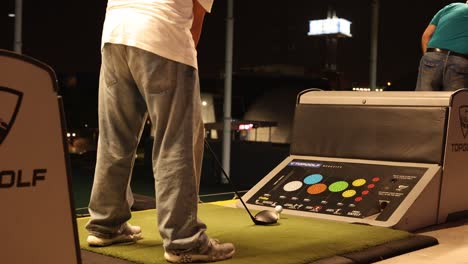 person practicing golf swings at topgolf facility