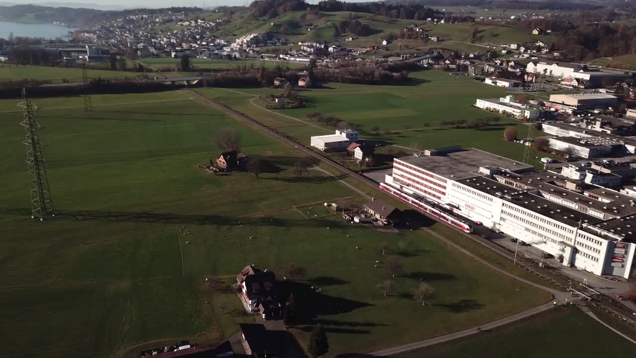 푸른 하늘 동안 배경, 언덕, 녹지 및 호수에서 지나가는 스위스 기차와 아름다운 풍경의 공중 패닝 샷