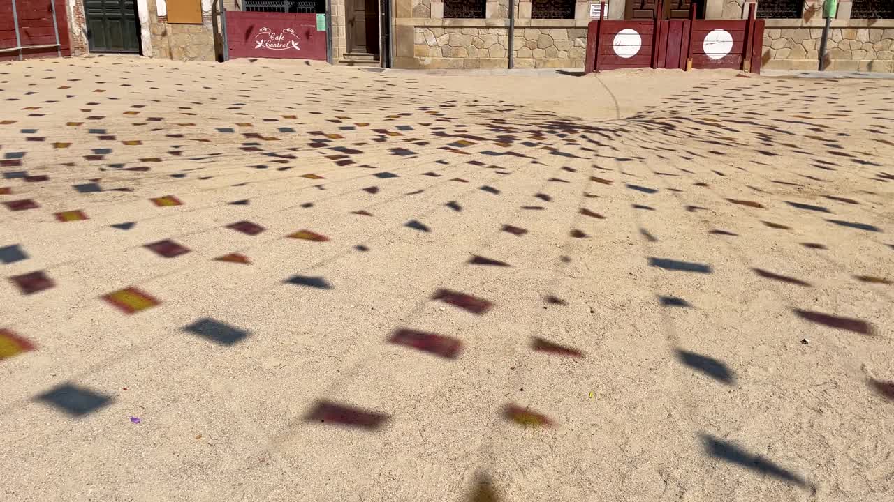 Striking footage of a town square at festivals where the shadows of the decorative flags appear on the ground followed by the town hall building and the tied flags, it is in slow motion