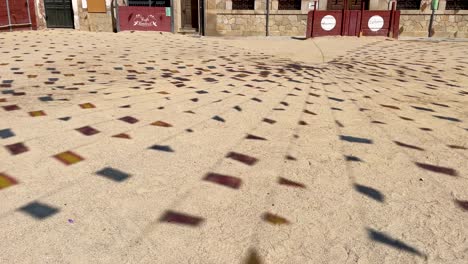 striking footage of a town square at festivals where the shadows of the decorative flags appear on the ground followed by the town hall building and the tied flags, it is in slow motion
