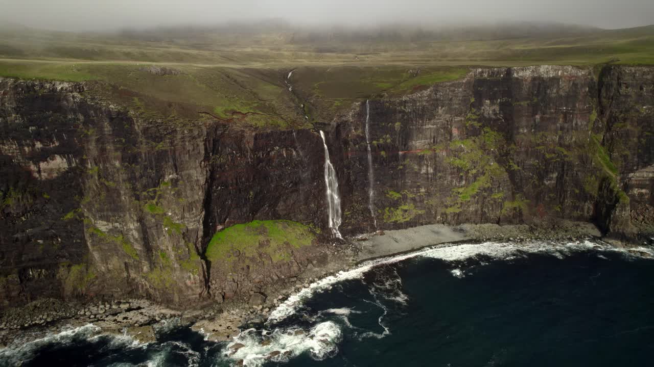 cascada prístina cae en cascada por el acantilado de la costa escocesa mientras el disparo se desvanece en las nubes