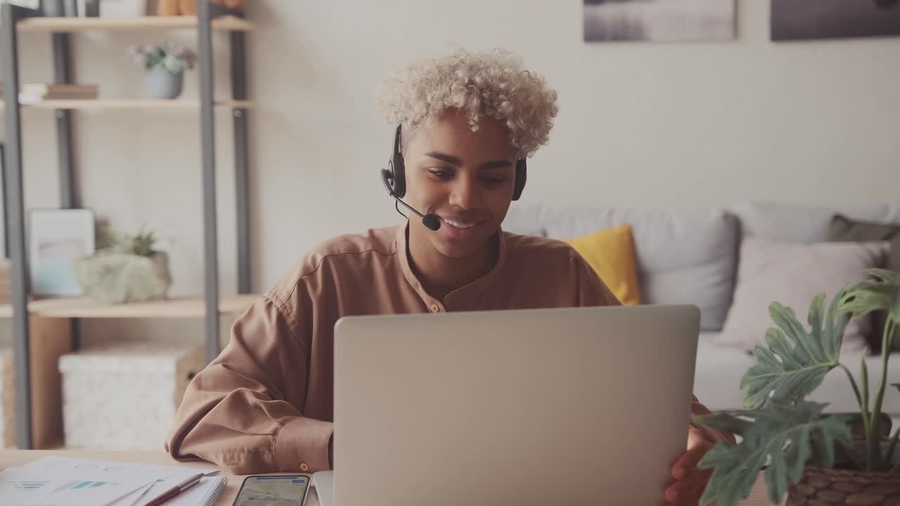 Dark skinned female wears headset conference video calling in home office