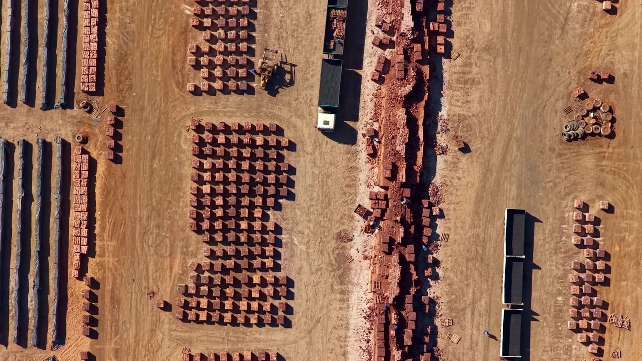 Top down aerial. Factory workers hand sorting clay building bricks at brickworks