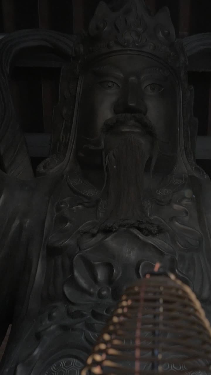 Incenso a spirale che brucia davanti a una statua tradizionale di divinità asiatica
